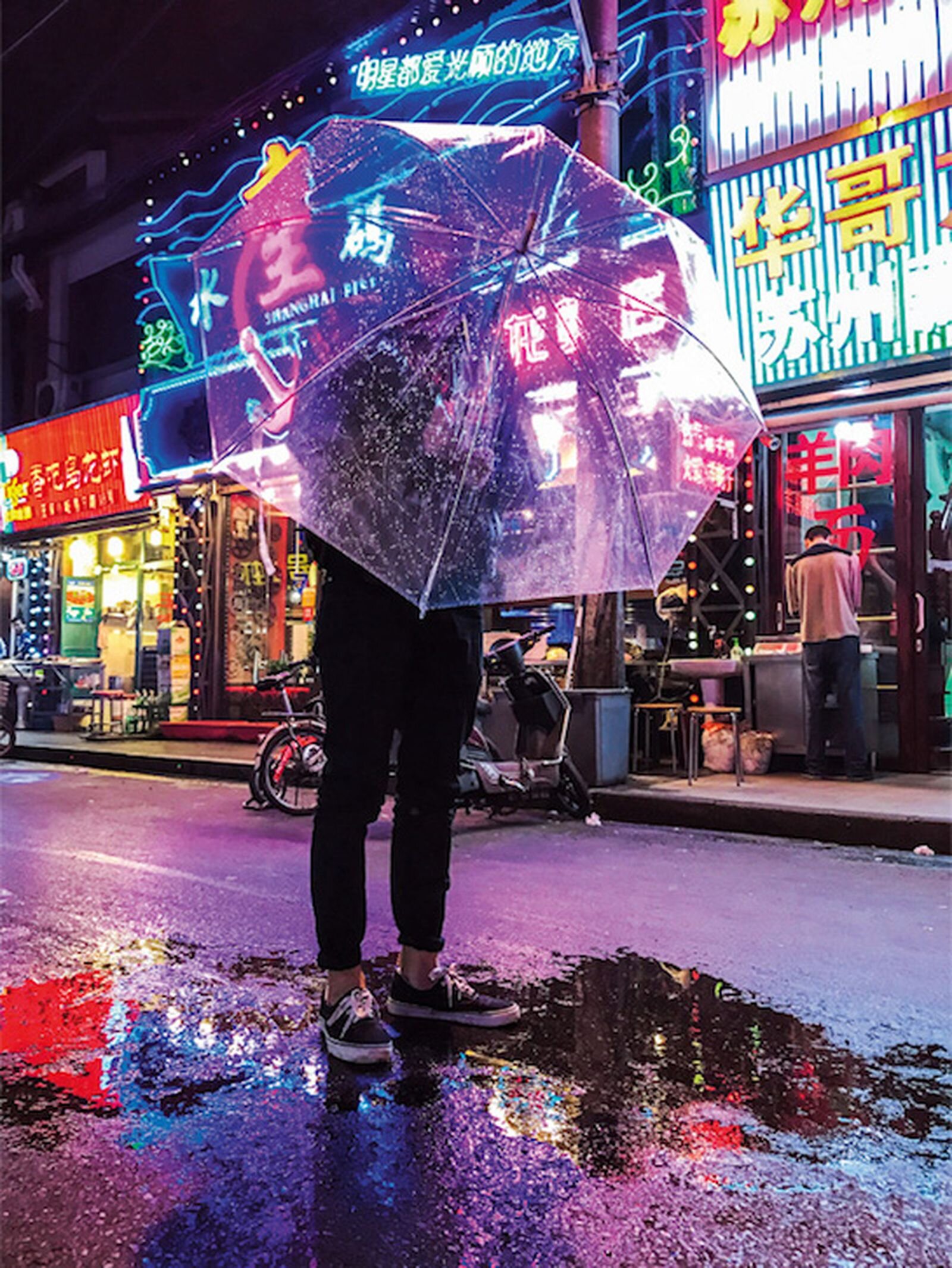 One Night on iPhone 7 campaign image: a person under a clear umbrella on a neon-lit Shanghai street at night