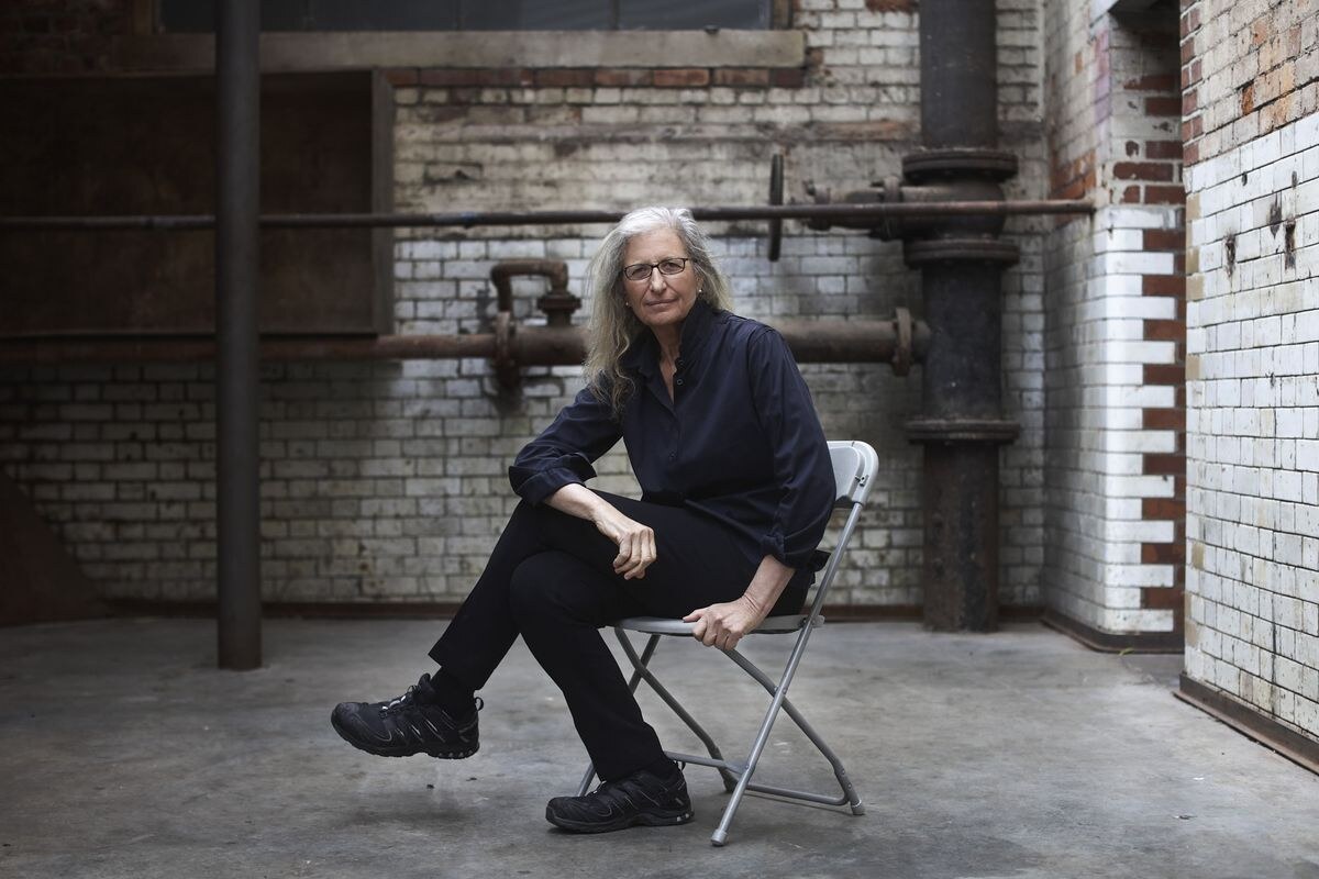 Portrait of Annie Leibovitz seated in an industrial exhibition space