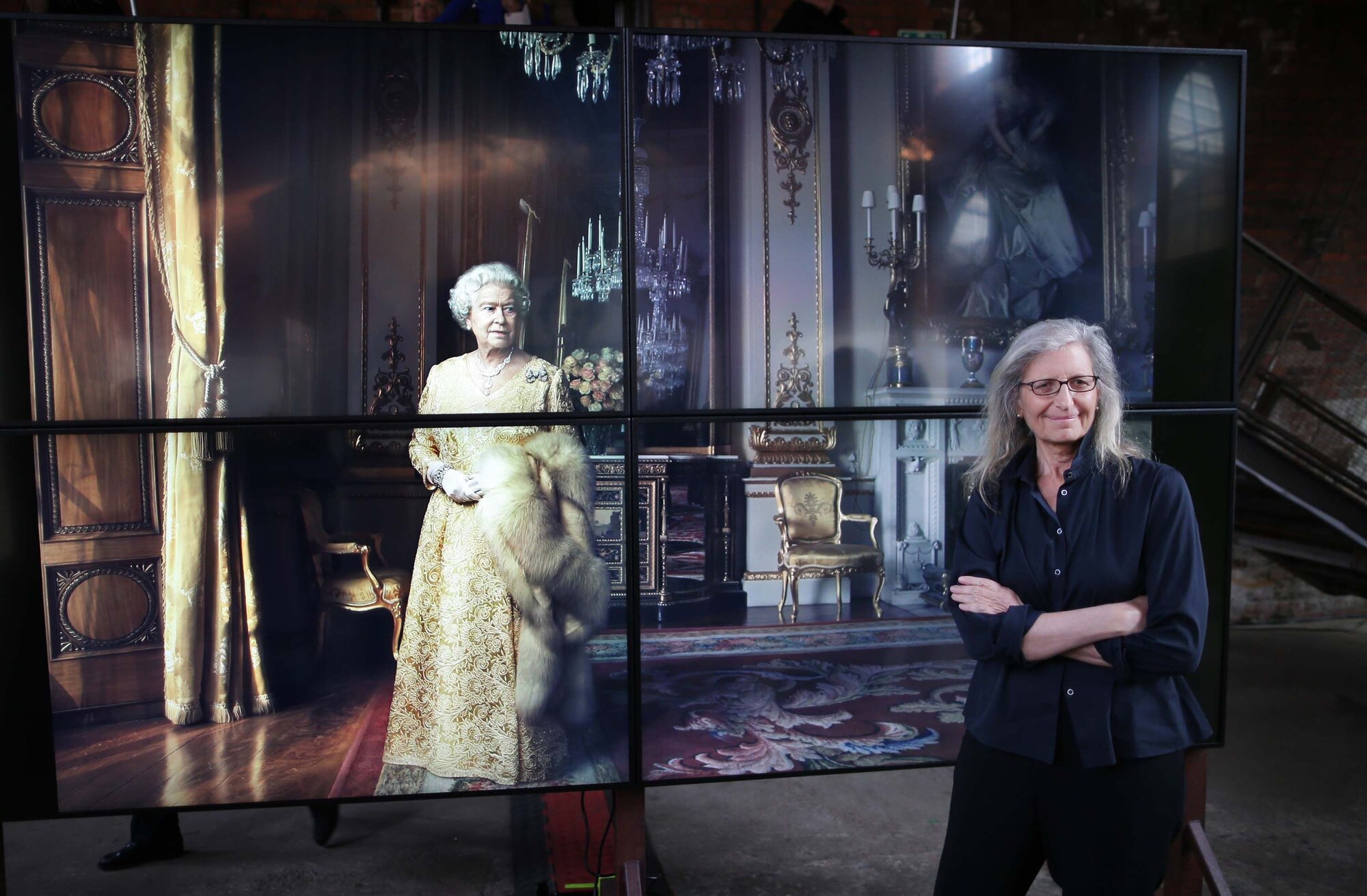 Annie Leibovitz beside the large multi-panel portrait of Queen Elizabeth II at the London exhibition