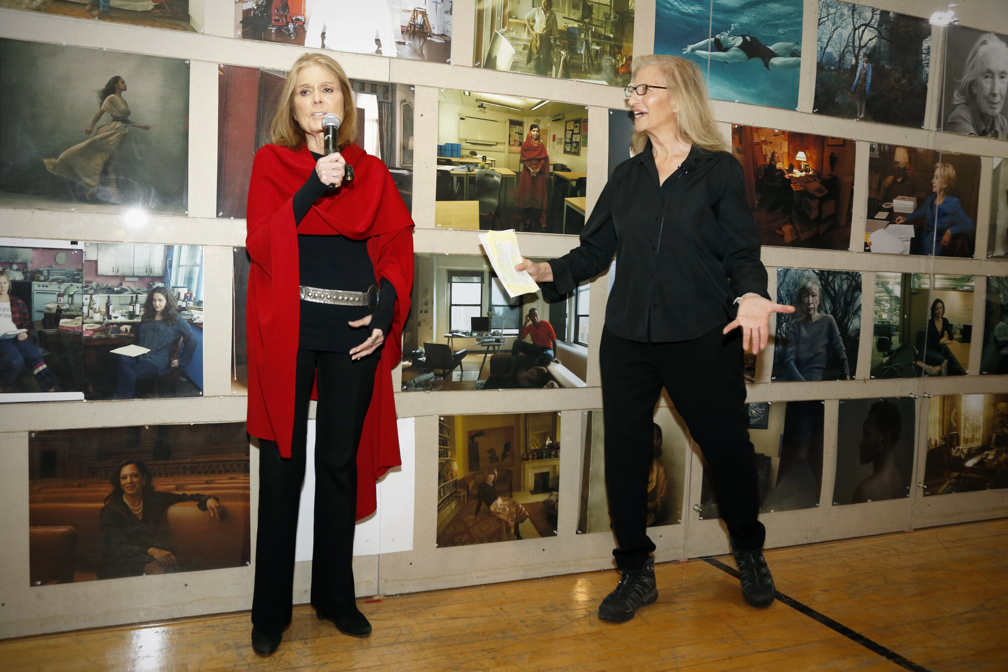 Annie Leibovitz in front of a colorful wall of portraits at the exhibition